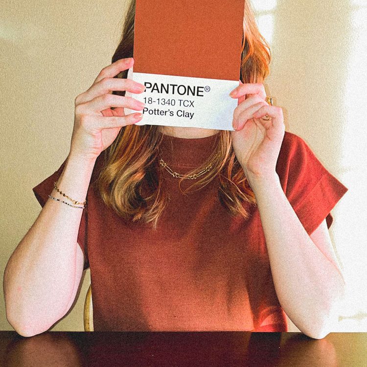 Image to represent branding and graphic design. Holding up a red color card typically used in determining brand colors.