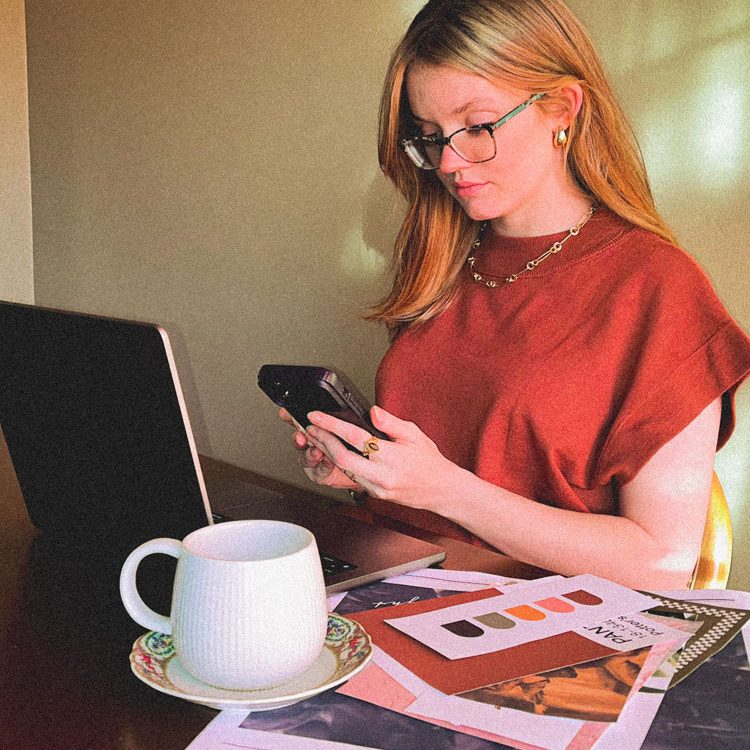 Image to represent social media services. Woman in red on her phone in front of a computer.